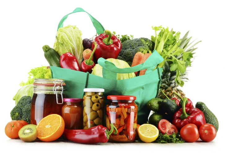 Green shopping bag with groceries isolated on white