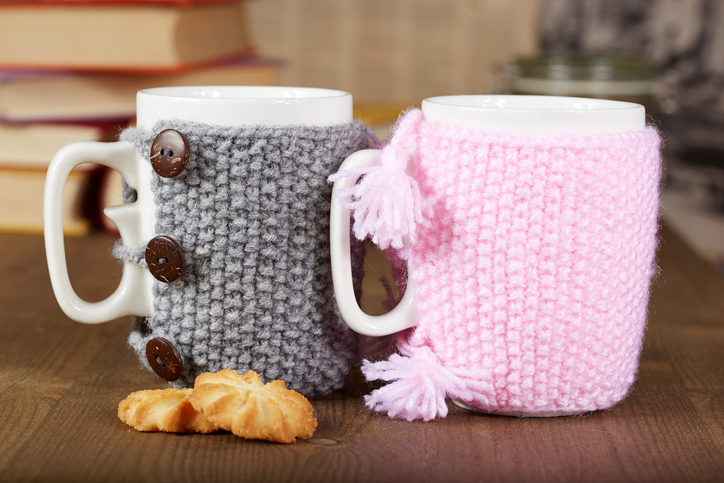 Couple of tea cups with knitted covers and biscuits